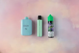 Three vaping products on a pastel background: a blue pod device, a green pod device, and a bottle of grape-flavored e-liquid.
